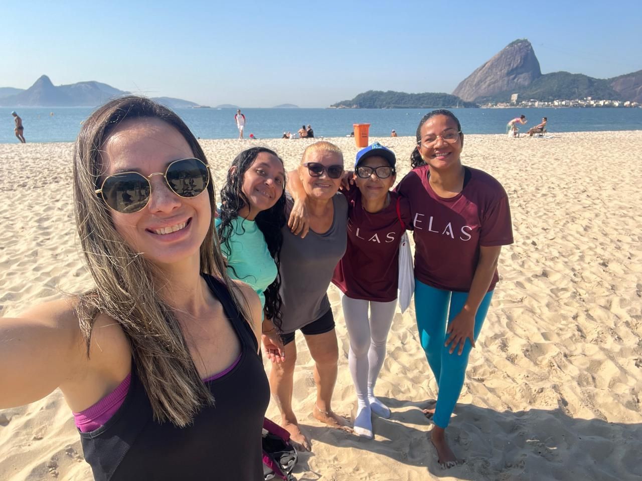 Participantes do Núcleo Elas após a ginástica funcional na praia, com o Pão de Açúcar ao fundo